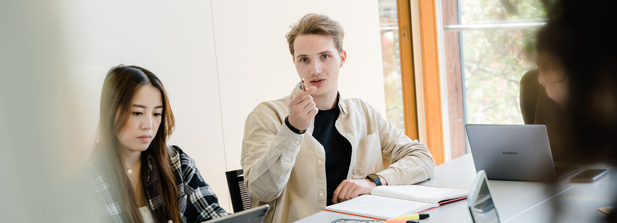 Studierende der HOK bei einer Gruppenarbeit im hellen Seminarraum.