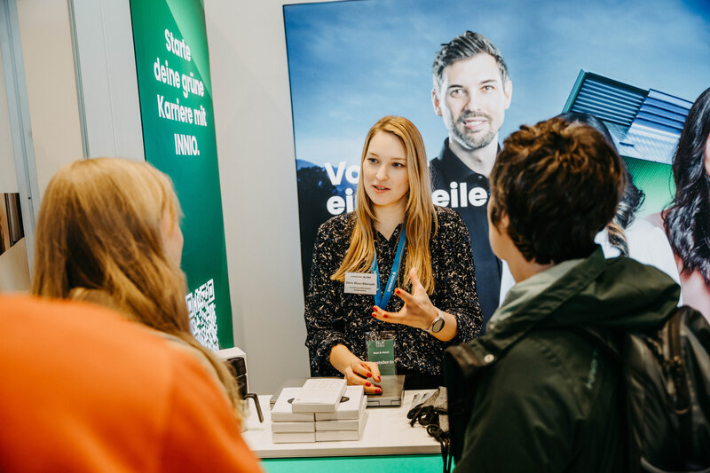 Innio-Stand auf der Meet & Match 2024 der HOK mit Standbetreiberin und Besucher:innen.
