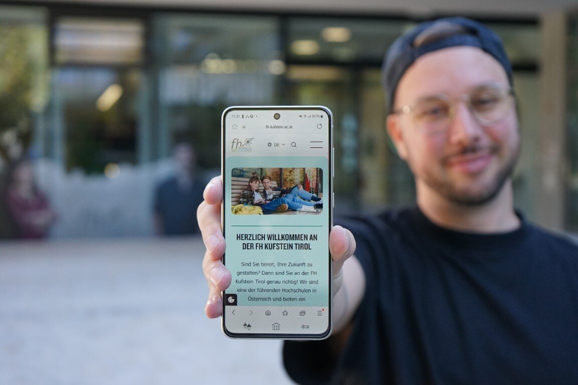 Student zeigt die mobile Version der neuen Website der HOK auf seinem Handy-Display.