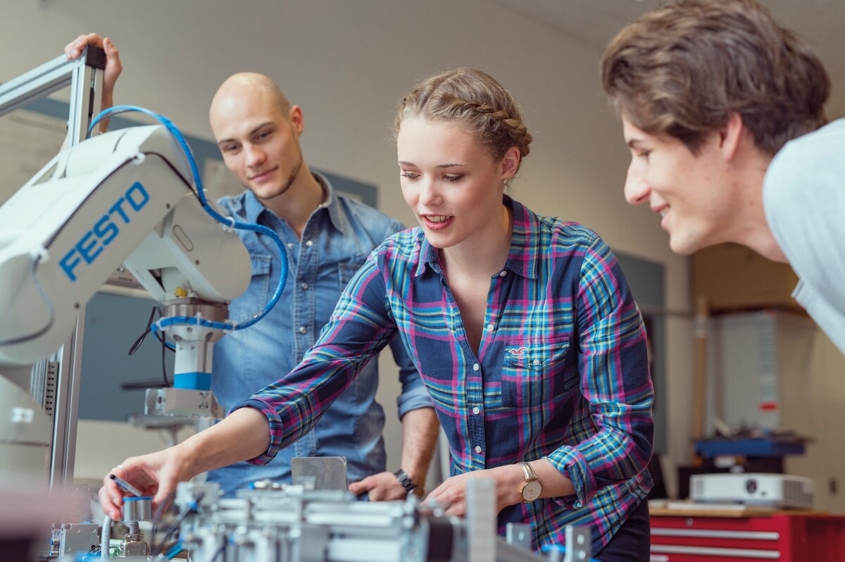 Studierende arbeiten gemeinsam an einer technischen Versuchsanlage mit Festo-Roboterarm im Labor der HOK.