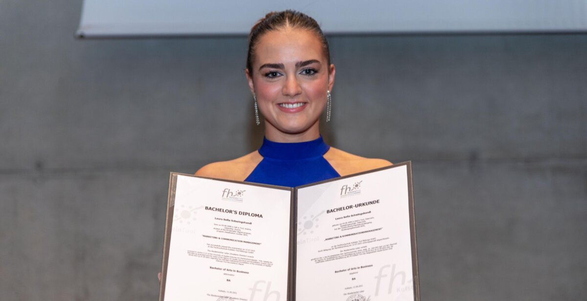 Laura Schwingshandl, Absolventin der HOK, hält ihre Bachelor-Urkunde stolz während der Sponsion 2021 in beiden Händen.