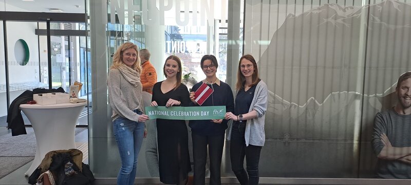 Vier Personen stehen vor dem Info Point mit einem Schild mit der Aufschrift National Celebration Day