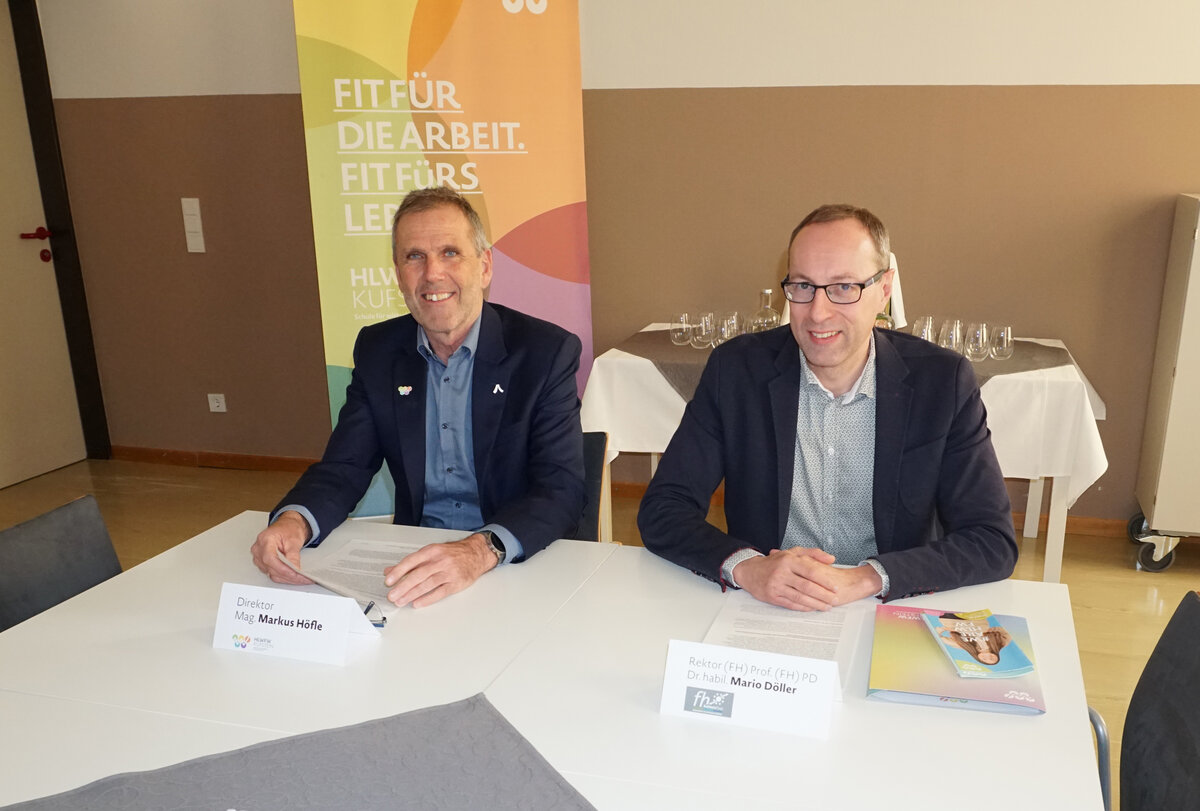 Der Direktor der HLW FW Kufstein, Mag. Markus Höfle, und der Rektor der HOK, Prof. (FH) Dr. Mario Döller, bei einem gemeinsamen Termin. Im Hintergrund ist ein Banner mit dem Slogan „Fit für die Arbeit. Fit fürs Leben.“ zu sehen.