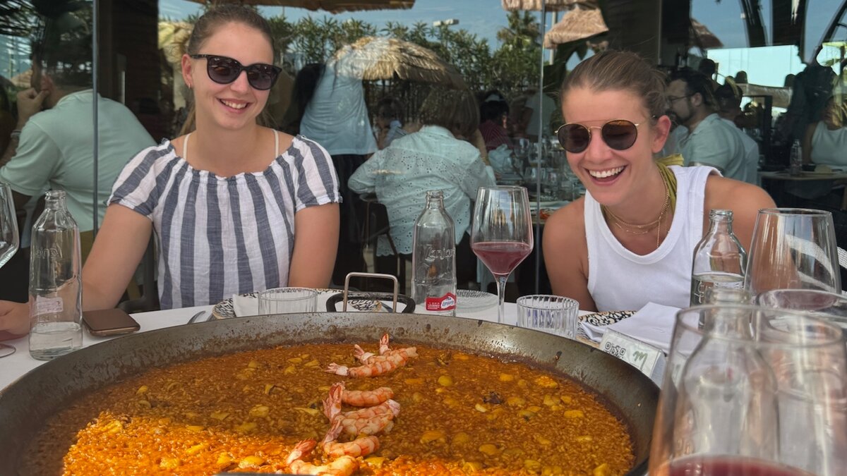 Digital Marketing-Studierende in Valencia vor eine Pfanne Paella.