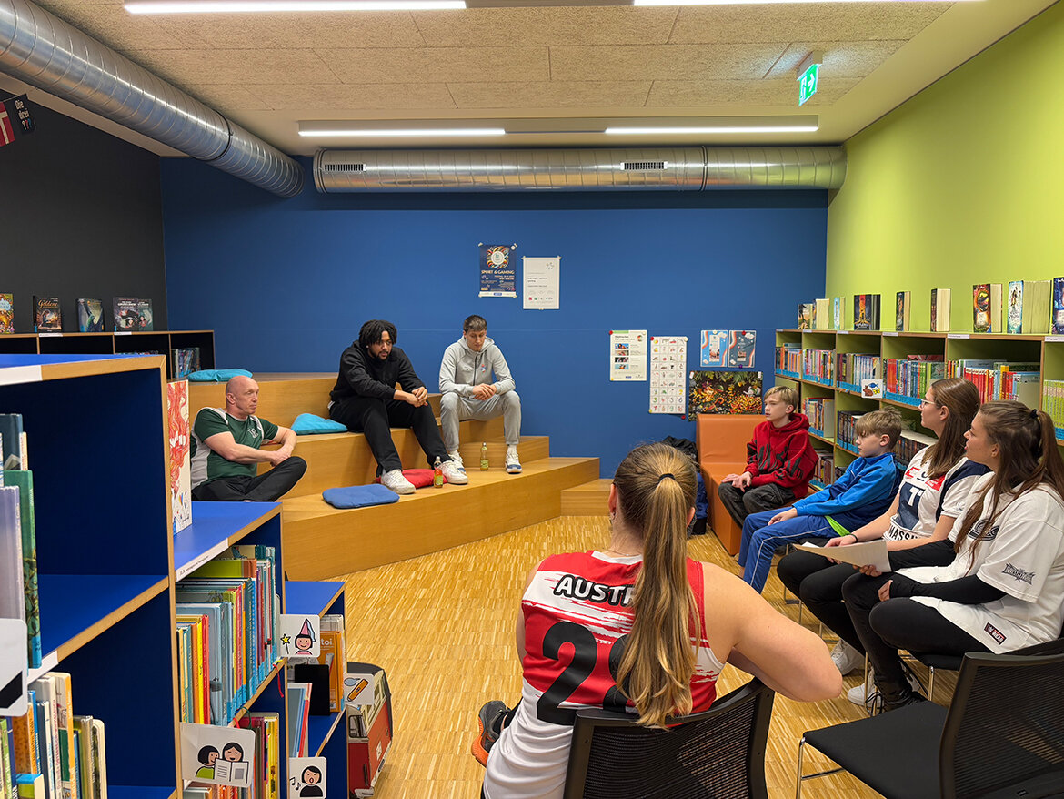 Kinder sitzen um zwei Personen im Leseraum der kubi