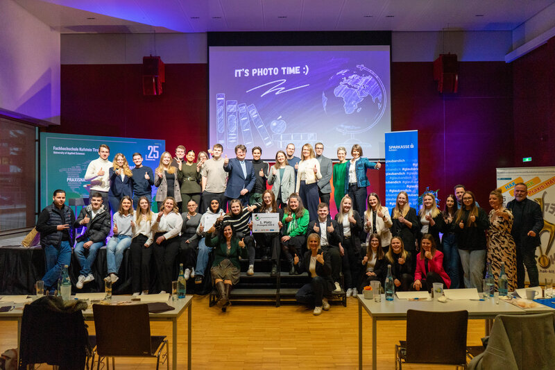 Ein abschließendes Gruppenbild mit allen Beteiligten des 7 € Cash@School-Wettbewerbs, darunter die Jury, die Organisatorin, die Praxisprojektgruppe, Schüler:innen und weitere Beteiligte.
