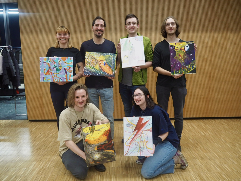 Personen stehen mit ihren Bilder für ein Gruppenbild zusammen