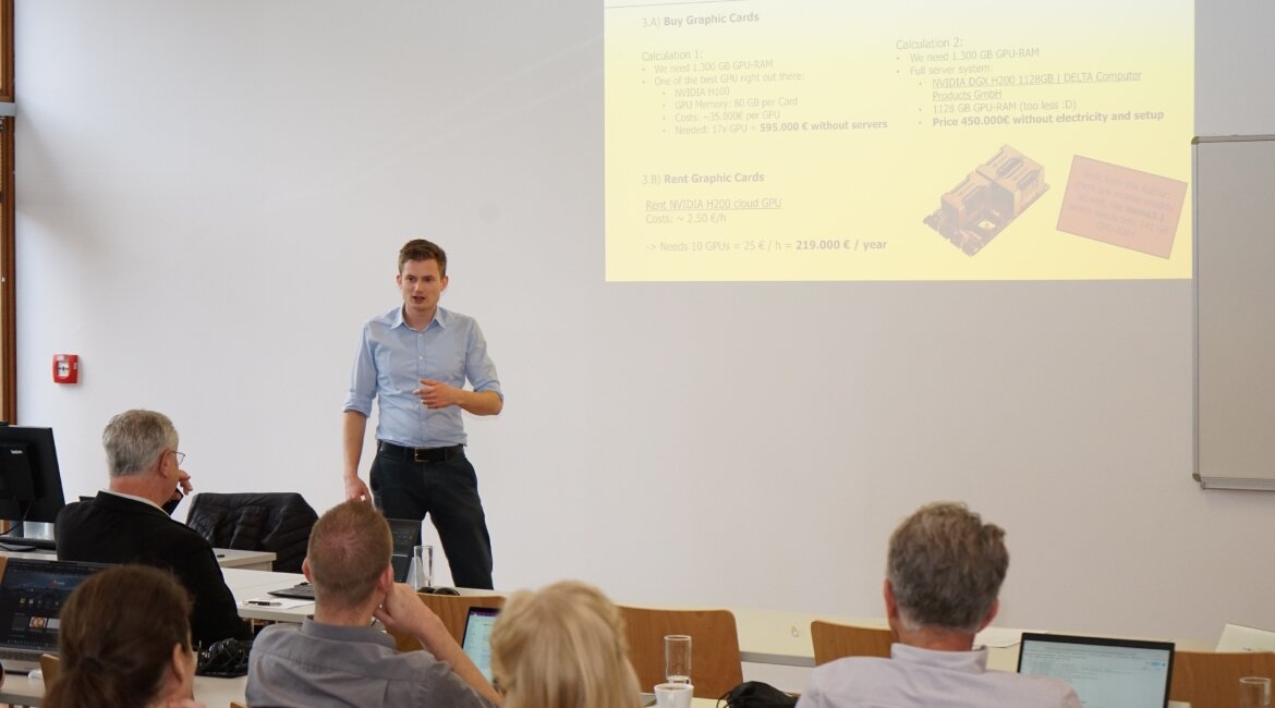 Alexander Schiegl hält einen Vortrag beim Workshop über den Einsatz von KI-Agenten im Marketing an der HOK. Die Präsentation im Hintergrund zeigt Berechnungen zu Grafikkartenkosten.