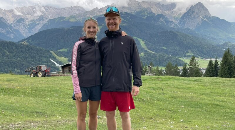 Lea und Stefan bei einer Wanderung, im Hintergrund ist ein Bergpanorama zu sehen. 