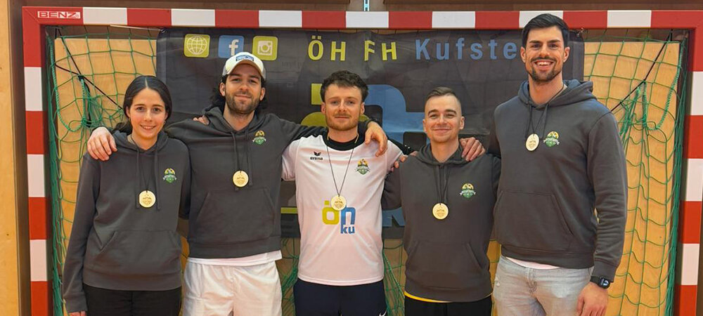 Fünf Personen, davon eine Frau, haben den Arm umeinander gelegt und stehen in einem Fußballtor.