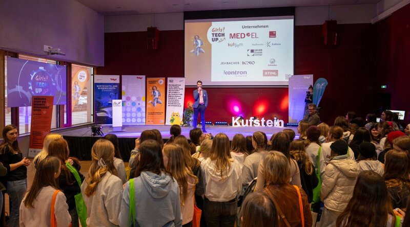 Auftakt zum Girls! TECH UP Day an der HOK. Das Foto zeigt den Besucher:innen im Festsaal sowie einen Speaker am Podium. 