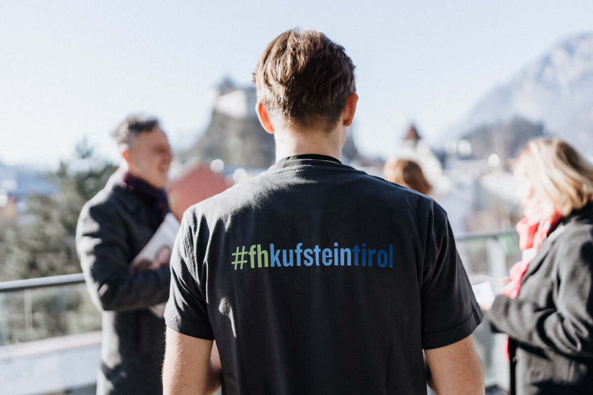 Ein Student auf der Dachterrasse der Hochschule.  Im Hintergrund sind die Umrisse der Festung zu sehen. 