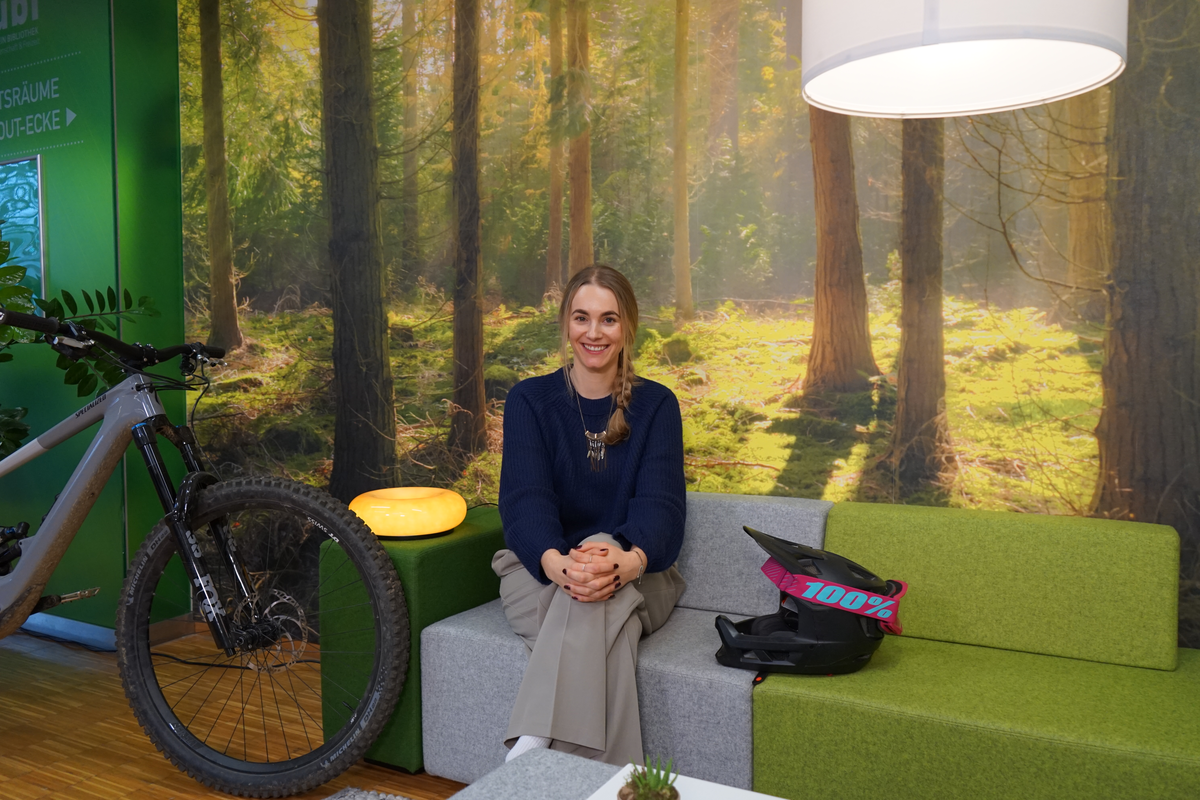 Masterstudentin Simone Kellner sitzt in der Bibliothek der HOK auf einer grün-grauen Couch und spricht über ihre Mountainbike-Leidenschaft und ihr Engagement für Inklusion.