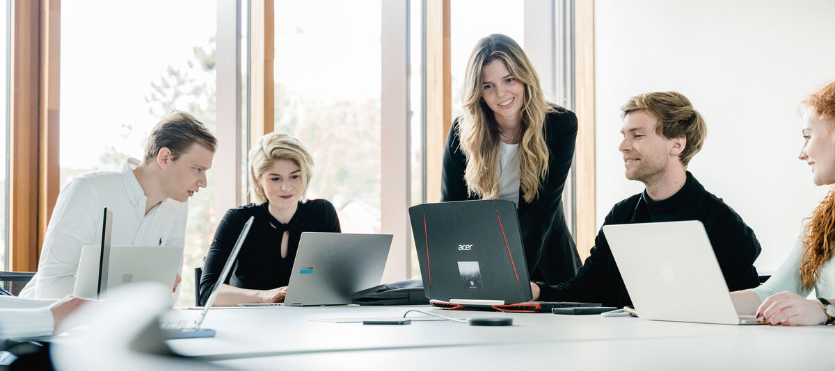 Personen sitzen nebeneinander und arbeiten am Laptop