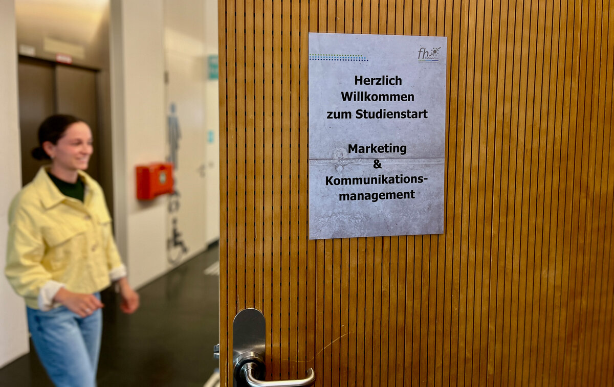 Schild mit Hinweis zum Aufnahmegespräch, Bewerberin tritt vor die Tür