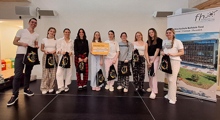 Lehrer und Schülerinnen mit Scheck und Stofftaschen