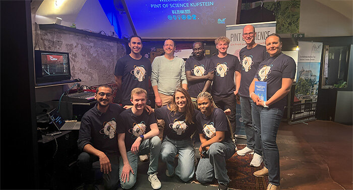 Eine Gruppe von Menschen steht gemeinsam in einem Raum. Einige haben die gleichen T-Shirts an.