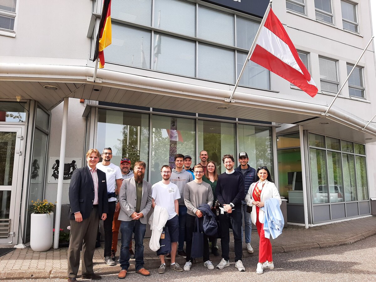 Eine Gruppe von Menschen steht vor einer gläsernen Fassade.