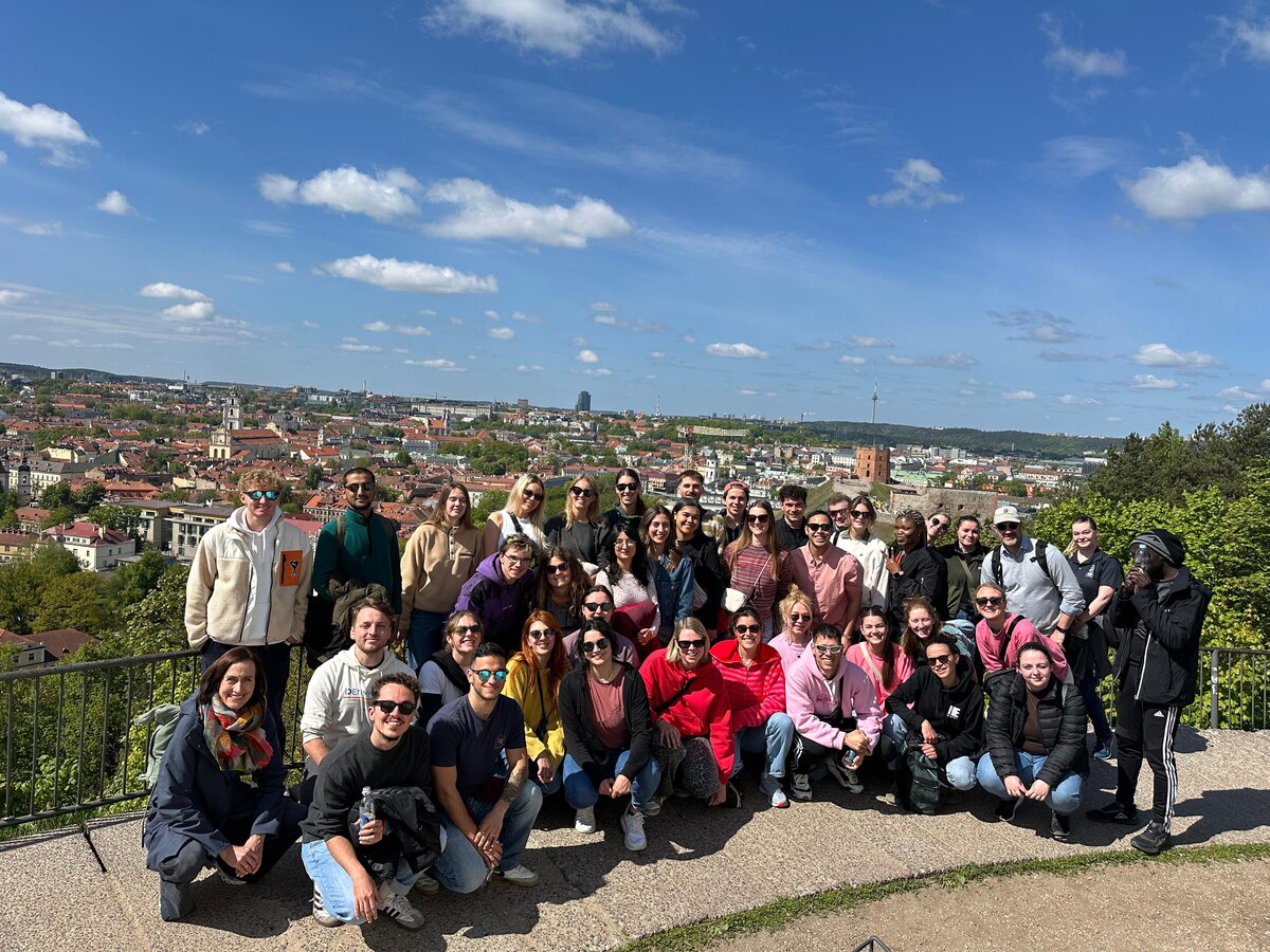 Eine Gruppe von Personen steht draußen, im Hintergrund eine Stadt.