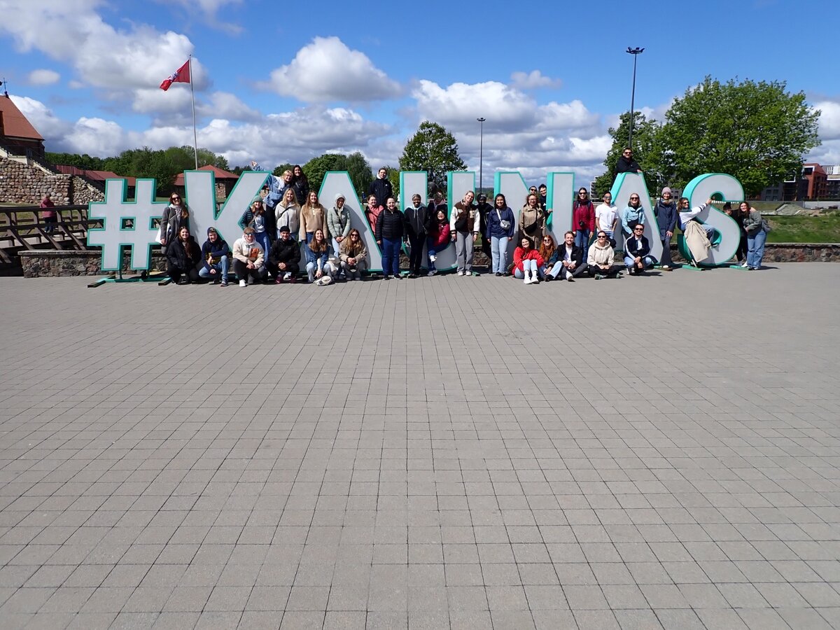 Eine Gruppe Menschen ist vor einem überlebensgroßen Schriftzug platziert.