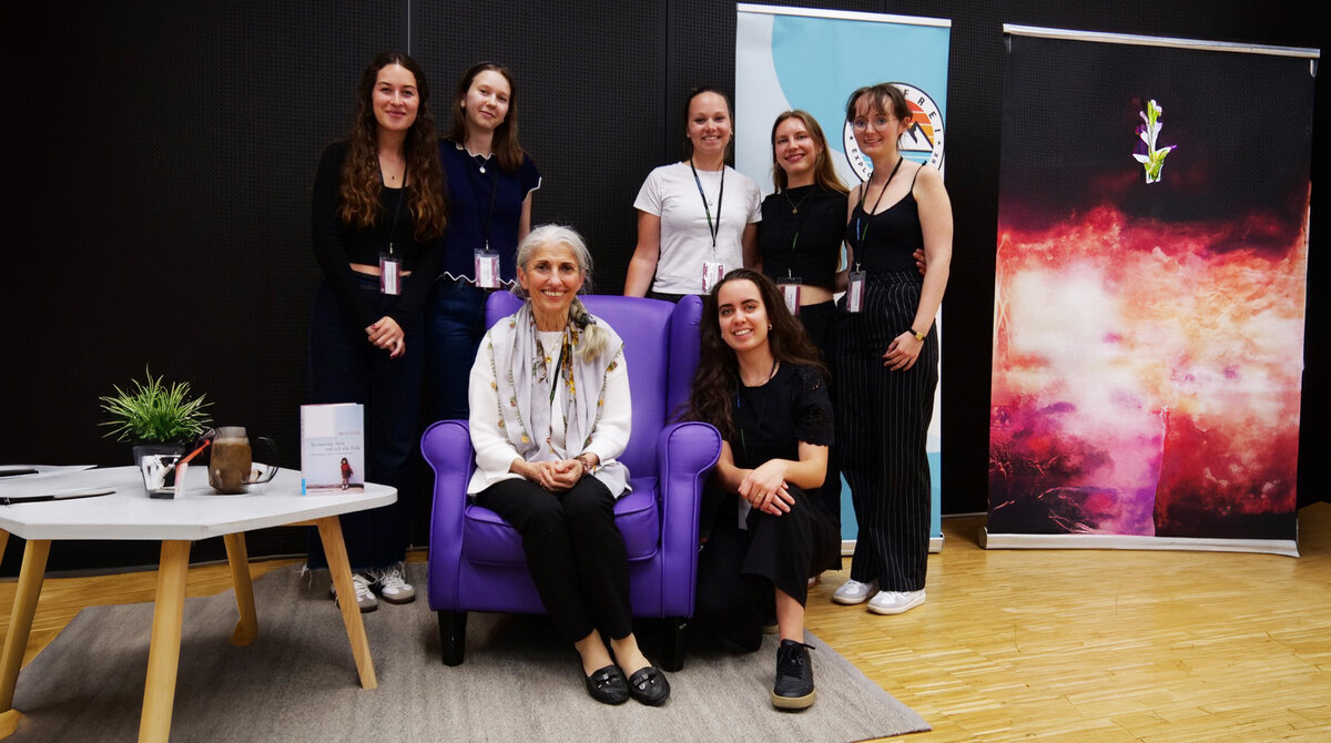 Gruppenfoto mit Autorin sitzend in einem violetten Sessel