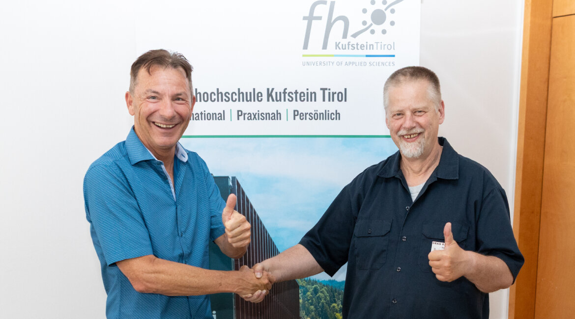 Zwei Männer beim Handschlag mit Daumen hoch.