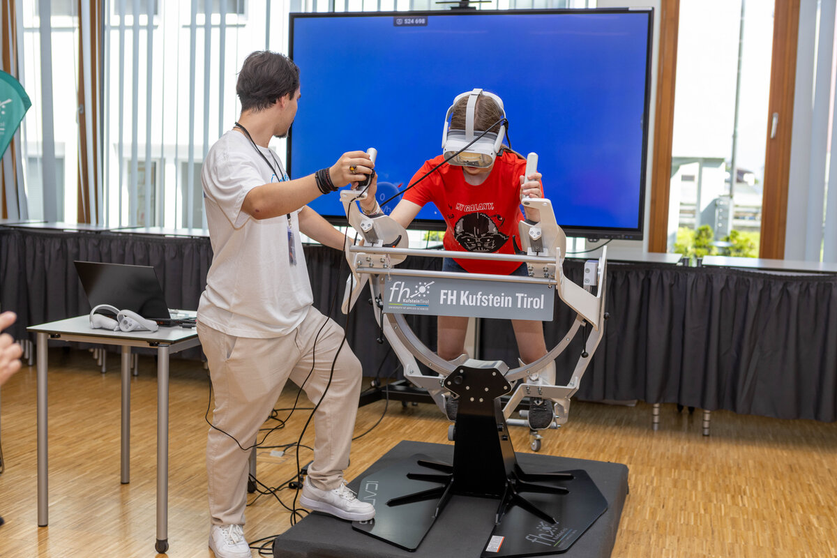 Ein Student der HOK betreut ein Kind, das mit VR-Brille und dem Flugsimulator „Icaros“ ein digitales Erlebnis ausprobiert.