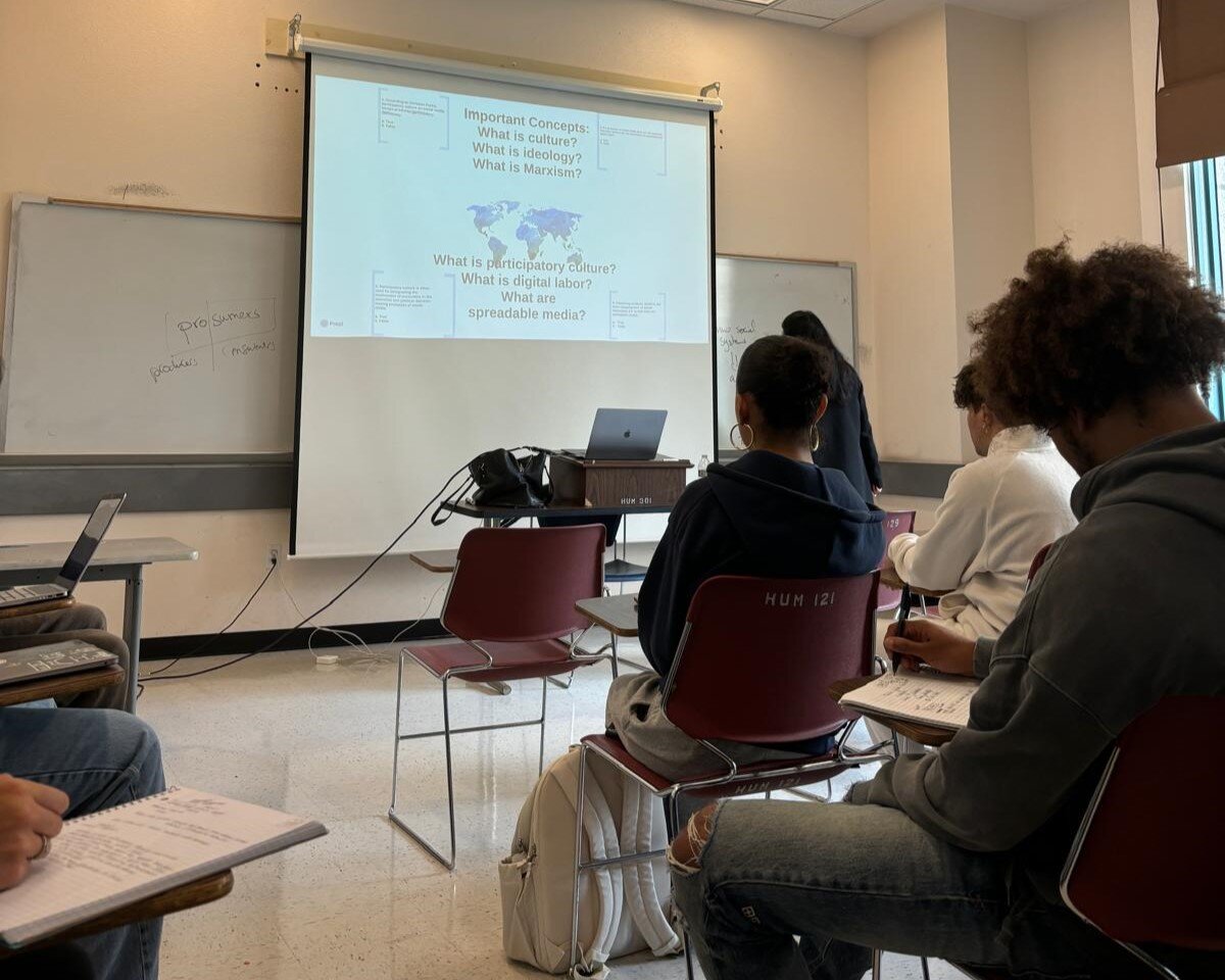 Studierende sitzen in einem Seminarraum in San Francisco und folgen einer Vorlesung mit Präsentation zu Kultur und Medien