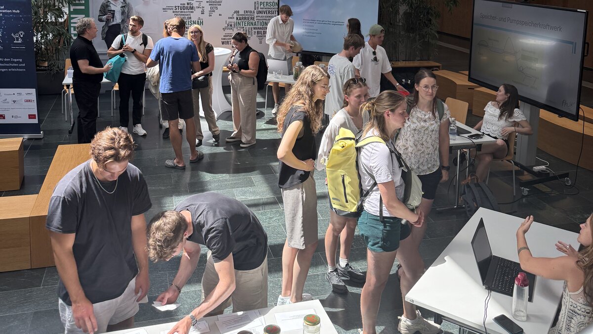 Mehrere Studierende und Besucher:innen stehen in der Aula der HOK bei den Sustainability Days 2025, informieren sich an Ausstellungsständen und diskutieren über nachhaltige Energielösungen.