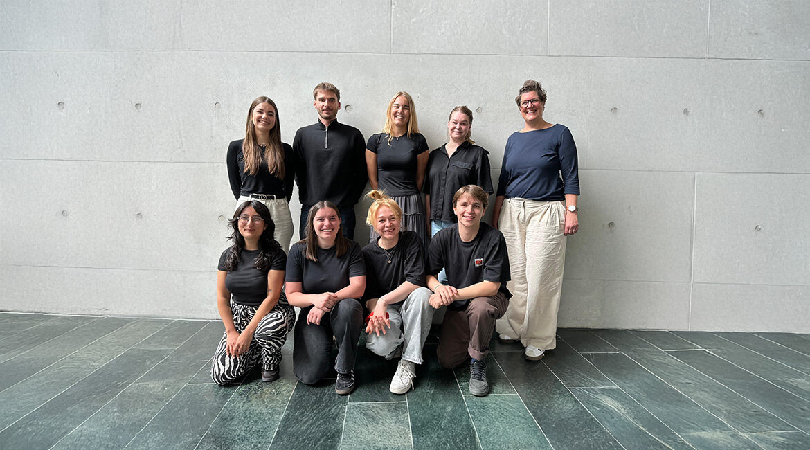 Gruppenfoto von acht Studierenden und einer Professorin der HOK vor einer Betonwand, die gemeinsam das Kurzfilmfestival organisieren.