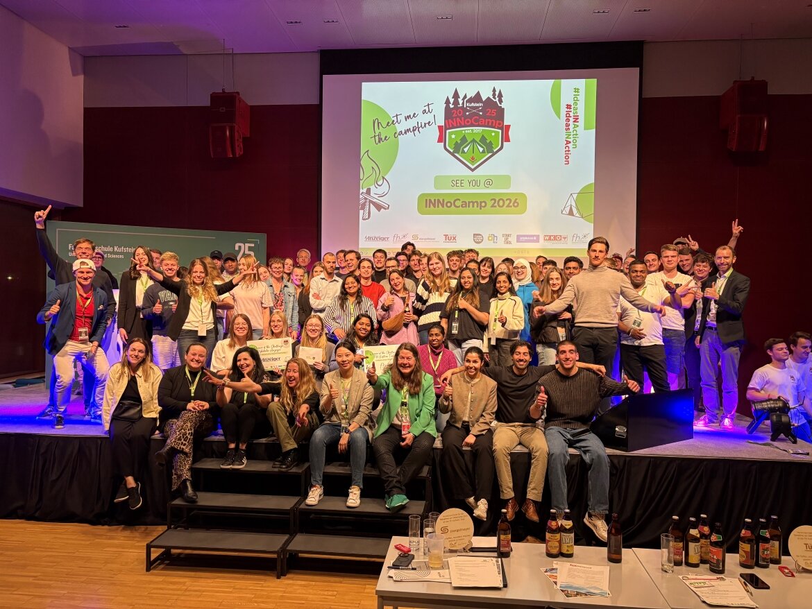 Große Gruppe von Studierenden und Teilnehmenden auf einer Bühne bei der Abschlussveranstaltung des INNoCamp 2025. Im Hintergrund eine Präsentationsfolie mit dem Schriftzug „See you @ INNoCamp 2026“.