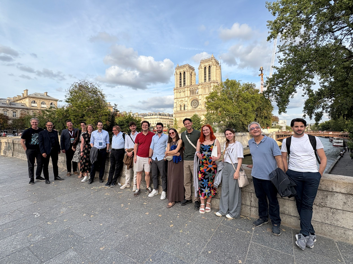 Eine Gruppe von TeilnehmerInnen der AIEST-Jahrestagung posiert bei sonnigem Wetter für ein Foto vor der Kathedrale Notre-Dame in Paris.