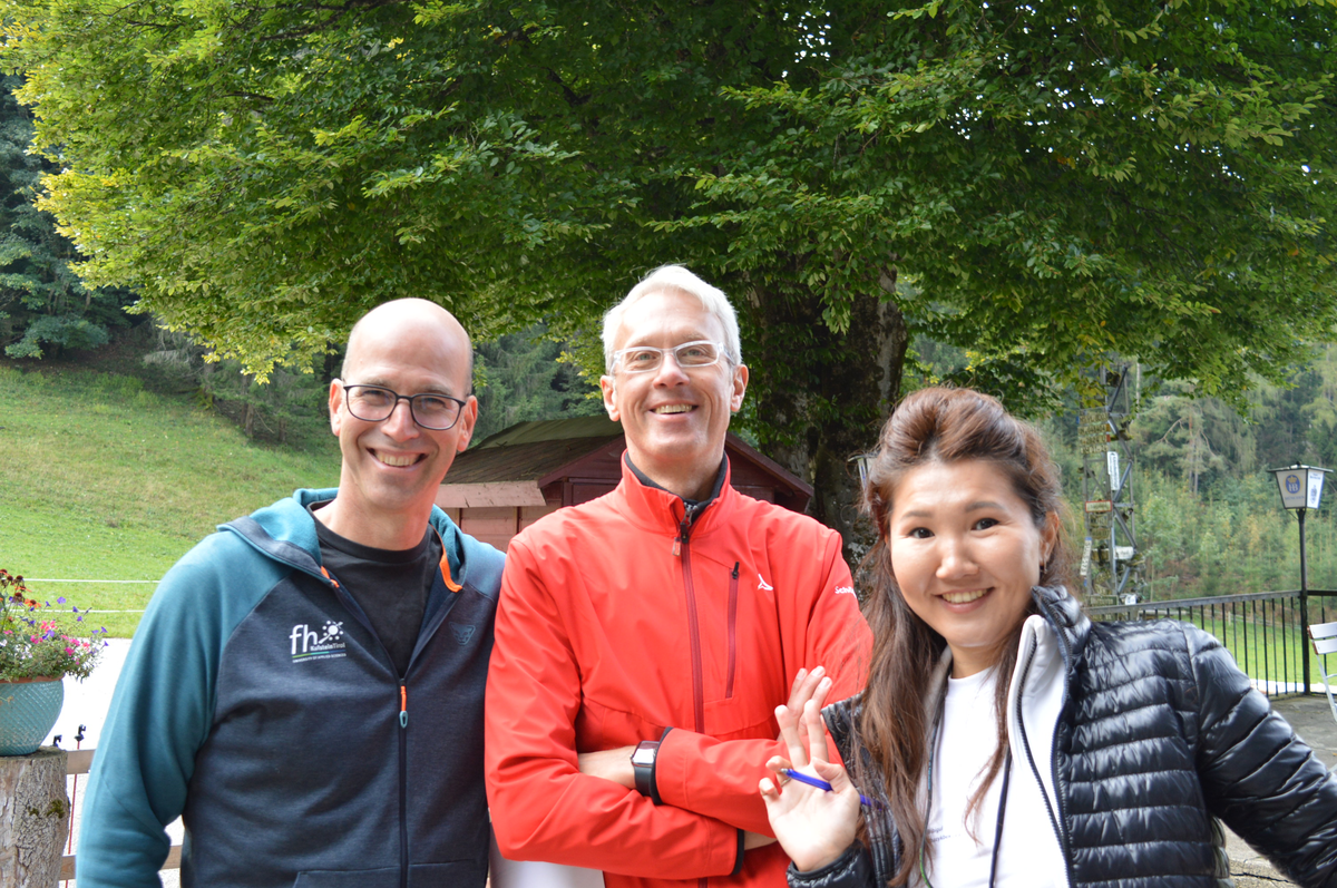 Drei lächelnde Personen des Studiengangs International Business Management stehen bei einer Wanderung am Hinterduxerhof beisammen.