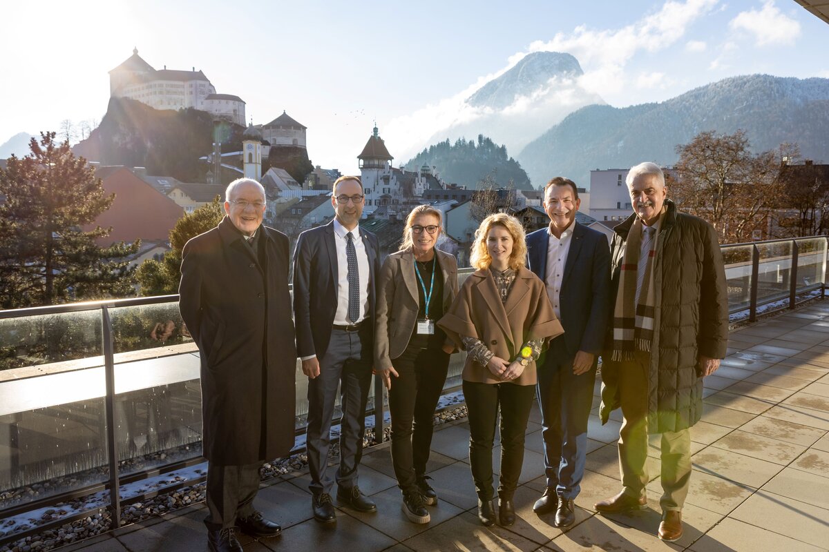 Gruppenfoto auf der Dachterrasse der HOK mit Vertreterinnen und Vertretern der Hochschulleitung und Bundesministerin Eva-Maria Holzleitner, im Hintergrund die Kufsteiner Festung.