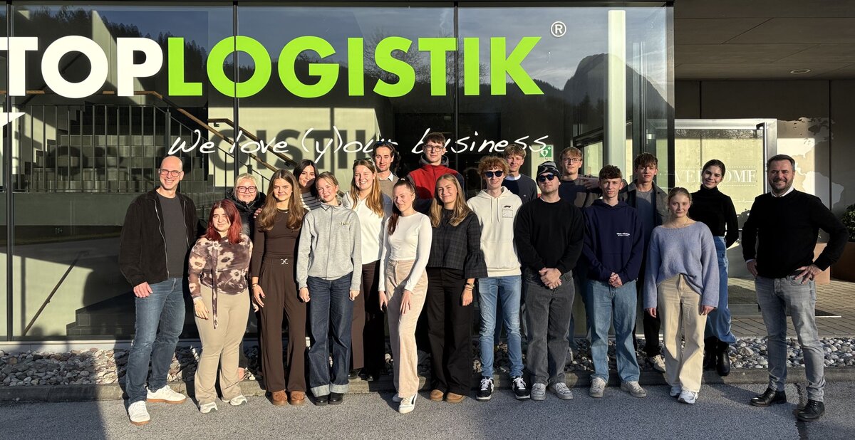 Eine Gruppe von Personen vor einer Glasfront eines Firmengebäudes.