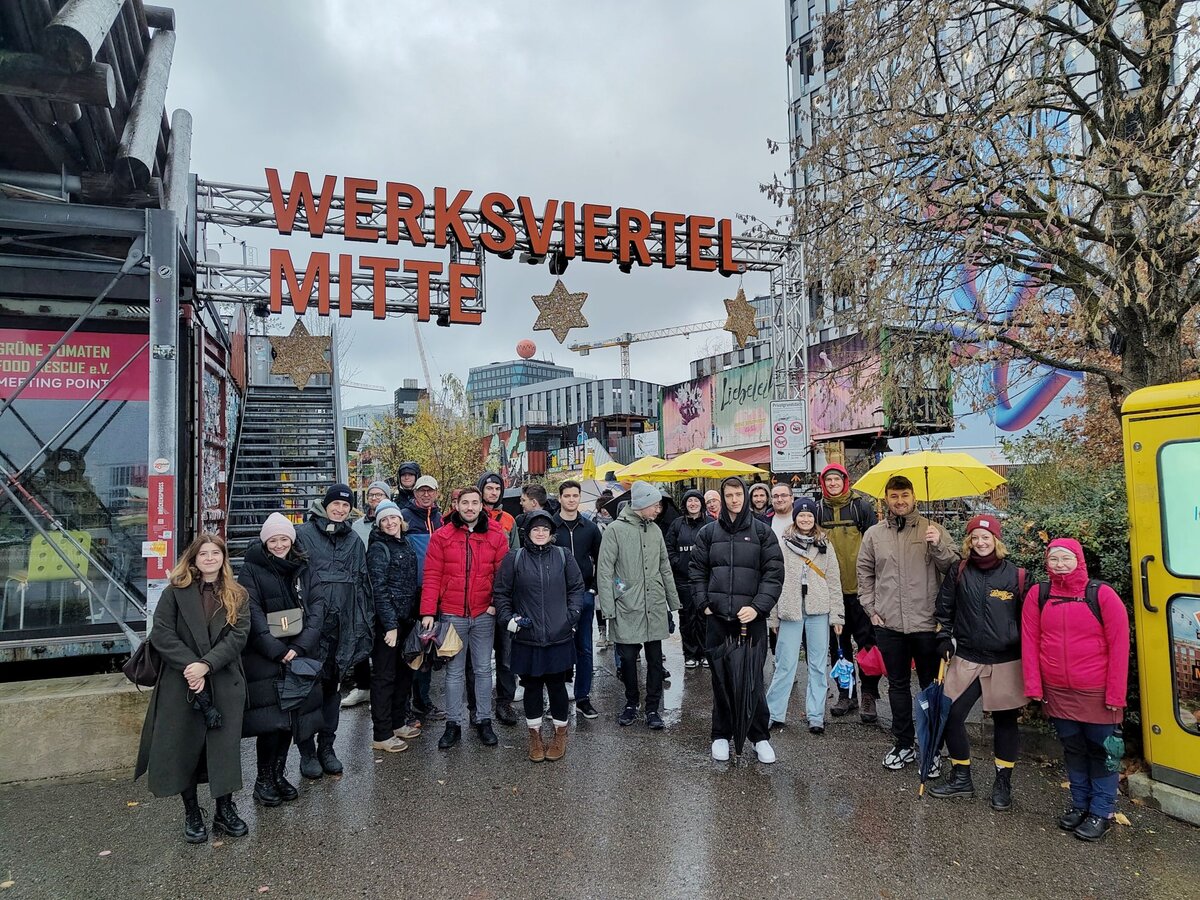 Eine Gruppe junger Leute steht in Winterkleidung vor einem Torbogen.