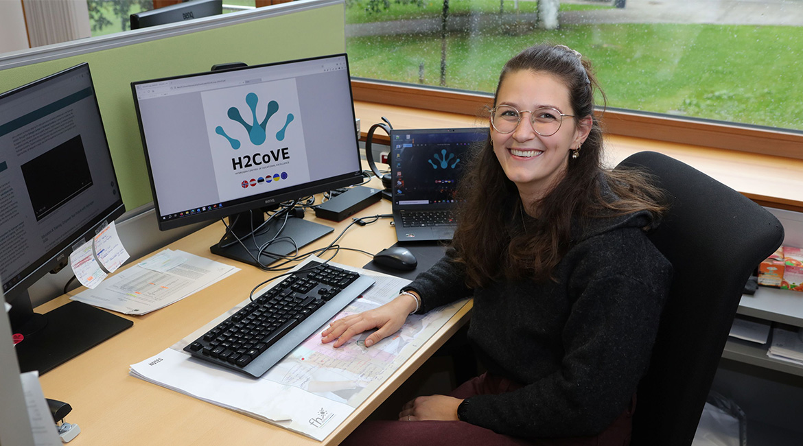 Franziska Boroviczény, wissenschaftliche Mitarbeiterin am Institut für Sustain & Estate, sitzt an einem Schreibtisch und blickt in die Kamera.