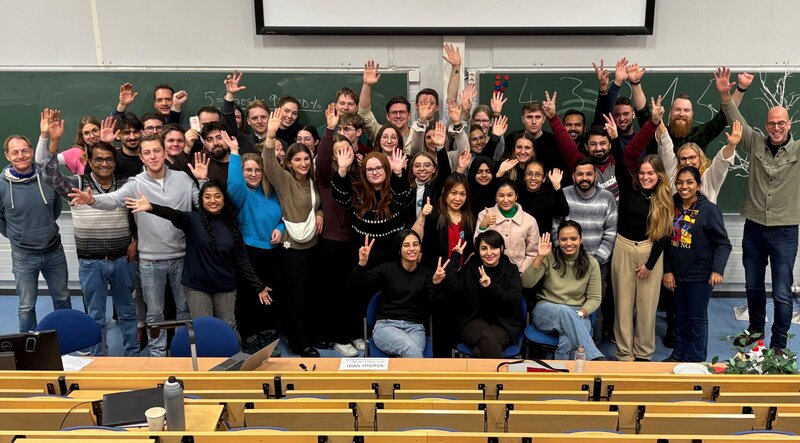 Teilnehmende stehen im Klassenraum für ein Gruppenfoto nebeneinander.
