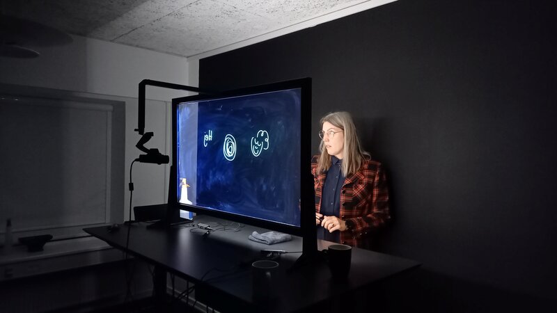 Person steht in einem dunklen Raum vor einem Transparenzdisplay.