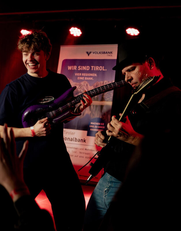 Zwei Personen spielen an der Gitarre.