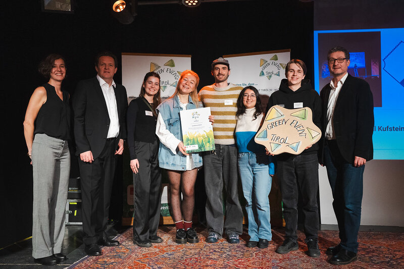 Gruppenfoto bei der Green Event Verleihung: Stephanie Rauscher, Landesrat René Zumtobel sowie Vertreter:innen der Kufsteiner Hochschule und des Festivals stehen nebeneinander und präsentieren die Kooperation.