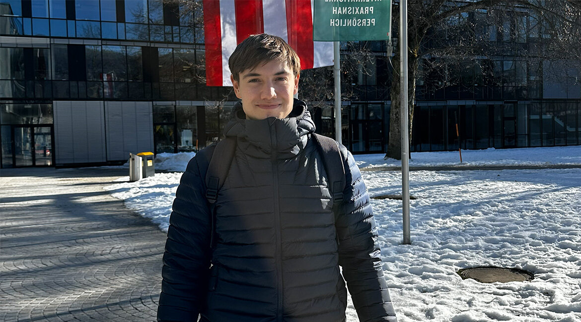 Person steht im Stadtpark Kufstein vor dem Hochschulgebäude