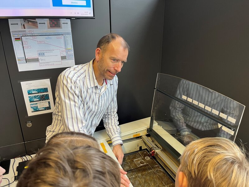 Markus Ehrlenbach erklärt den Schüler:innen wie der Lasercutter funktioniert.
