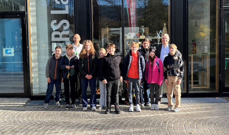 Schüler:innen mit Physiklehrer Christian Pronegg und Markus Ehrlenbach vor dem Gebäude der HOK.