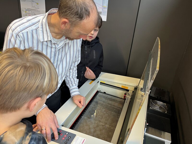 Markus Ehrlenbach zeigt den Schüler:innen wie der Lasercutter zu bedienen ist.