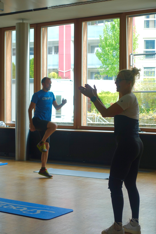 Trainerin steht motiviert vor der Sportgruppe in einer Vorlesungsraum