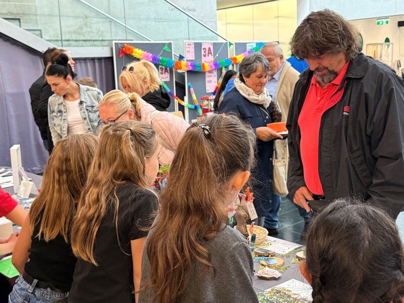 Besucher:innen betrachten die selbst produzierten Artikel an den Marktständen.