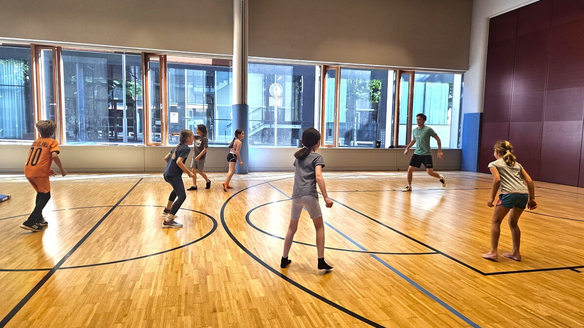 Kinder spielen in einer Sporthalle.