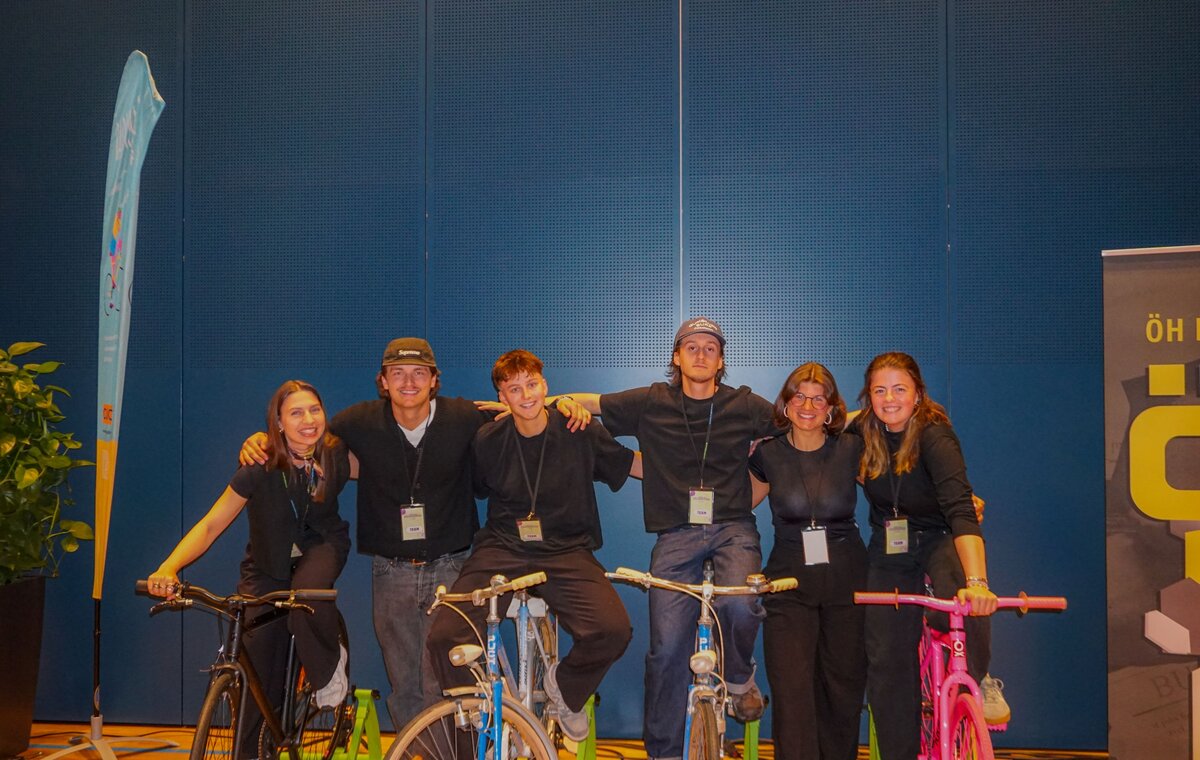 Praxisprojekt Team auf den Bikes vor einer blauen Wand.
