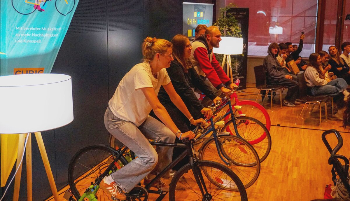 Zuschauer:innen auf den Bikes, sodass der Strom für den Film erzeugt werden kann.